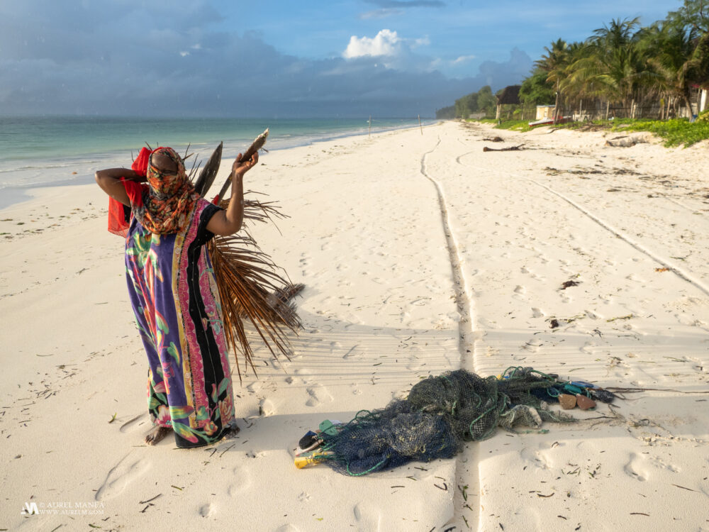 Woman carries a palm leaf on a Zanzibar beach 01